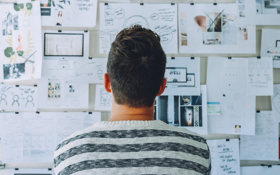 man looking at a whiteboard full of notes on pieces of paper